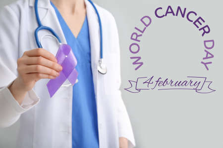 Female doctor with awareness ribbon on gray background. World Cancer Dayの写真素材