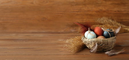 Nest with Easter eggs on wooden background with space for text