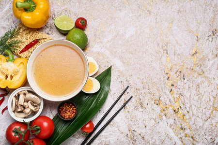 Bowl of tasty Thai soup and ingredients on grunge background