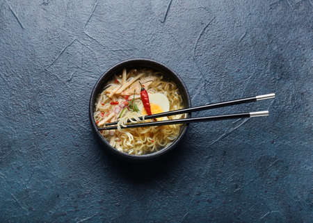 Bowl of tasty Thai soup with chicken on dark background