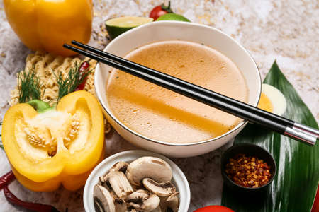Bowl of tasty Thai soup and ingredients on table