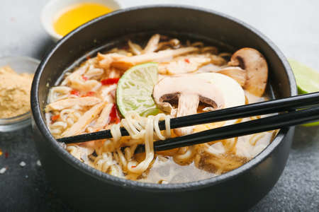 Bowl of tasty Thai chicken soup on table, closeup