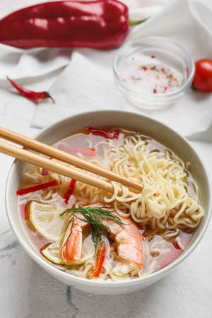 Bowl of tasty Thai soup with shrimps on light background