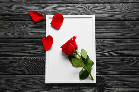 Beautiful rose and photo frame on dark wooden backgroundの写真素材