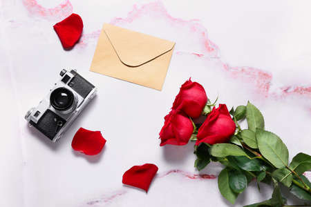 Beautiful roses, photo camera and envelope on light backgroundの写真素材