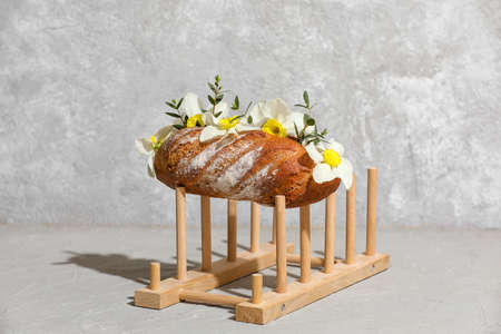 Creative composition with tasty fresh bread and flowers on gray background
