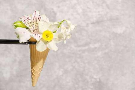 Creative composition with waffle cone and beautiful flowers on gray background, closeupの写真素材