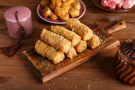 Board with delicious baklava on wooden background