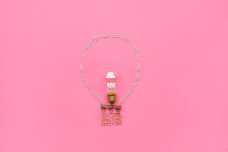 Light bulb made of stationery and lamp on color background