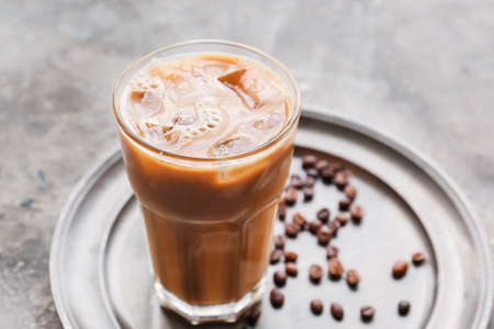 Glass of ice coffee with milk on grunge background, closeup