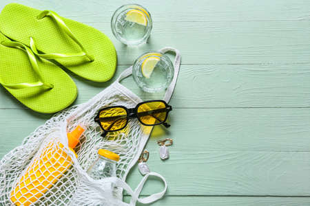 Stylish beach accessories with glasses of water on color wooden backgroundの写真素材