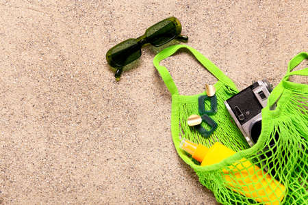 Stylish beach accessories with photo camera on sandの写真素材