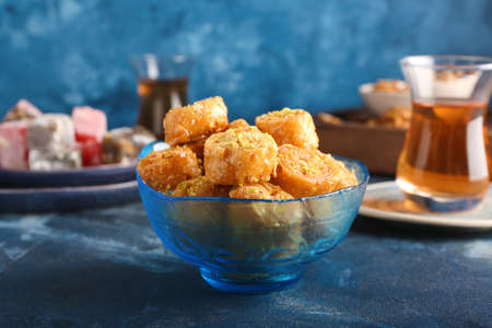 Bowl with delicious baklava on color backgroundの写真素材