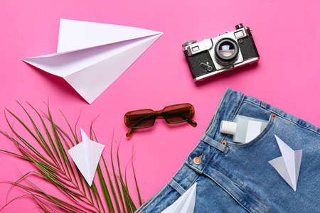 Stylish sunglasses with jeans pants, photo camera and paper airplanes on color backgroundの写真素材