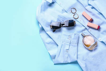 Stylish female accessories with clothes on color background