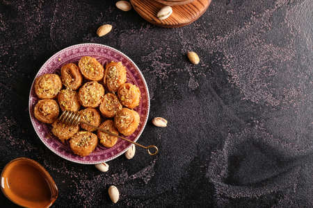 Plate with delicious baklava and honey dipper stick on dark backgroundの写真素材