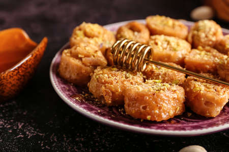 Plate with delicious baklava and honey dipper stick, closeupの写真素材