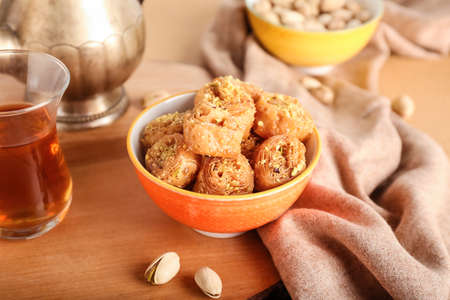 Bowl with delicious baklava and pistachio nuts on tableの写真素材