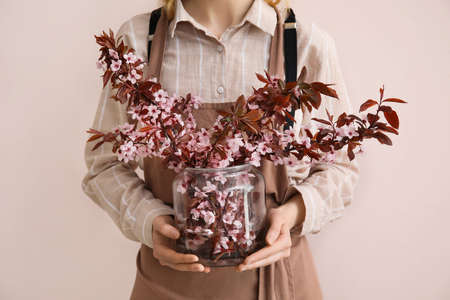 Woman with beautiful blossoming branches on color backgroundの写真素材