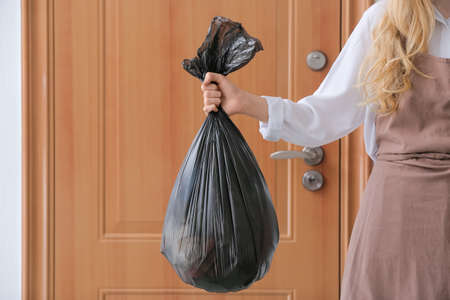 Woman holding bag with garbage at home, closeup