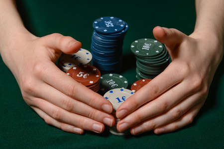 Female hands with poker chips on dark background