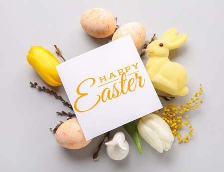 Easter greeting card, eggs, flowers and toy bunny on light backgroundの写真素材