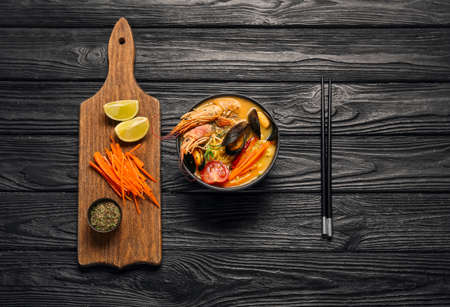 Bowl of tasty Thai soup on dark wooden background