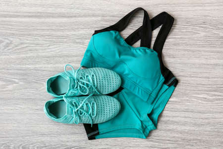 Sportswear and shoes on light wooden background