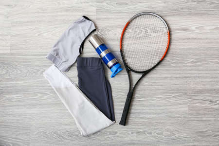 Sportswear, bottle for water and tennis racquet on light wooden backgroundの写真素材