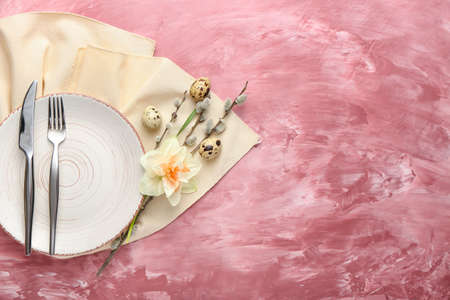 Beautiful table setting with narcissus flower and eggs on color background