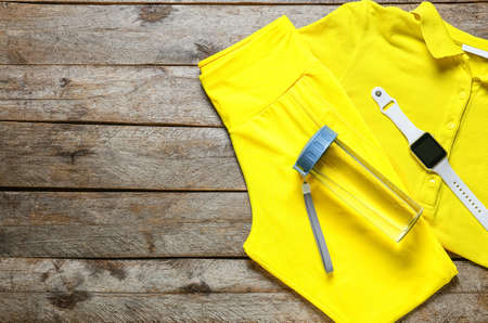Sportswear, bottle for water and smartwatch on wooden background