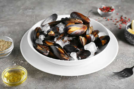 Bowl of tasty mussels with ice on grunge background