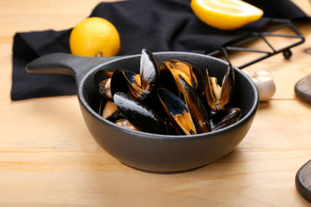 Frying pan with tasty mussels on wooden backgroundの写真素材