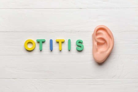 Word OTITIS and ear model on white wooden backgroundの写真素材