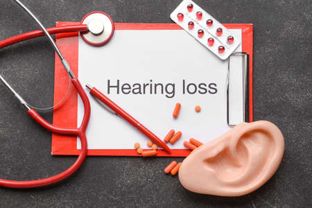 Clipboard with text HEARING LOSS, stethoscope and ear model on dark backgroundの写真素材
