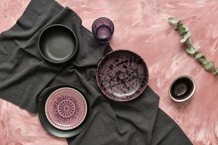 Stylish tableware and black napkin on color backgroundの写真素材