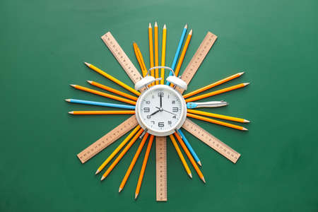 Alarm clock with stationery around on green backgroundの写真素材