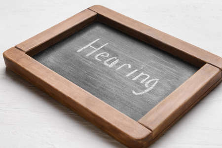 Chalk board with word HEARING on white wooden backgroundの写真素材