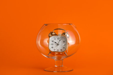 Vintage alarm clock inside glass vase on orange backgroundの写真素材