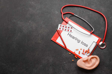 Clipboard with text HEARING LOSS, stethoscope and ear model on dark backgroundの写真素材