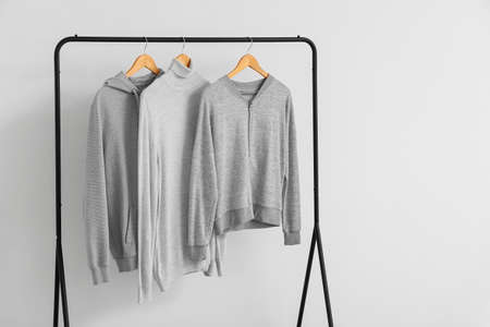 Rack with warm clothes near light wall