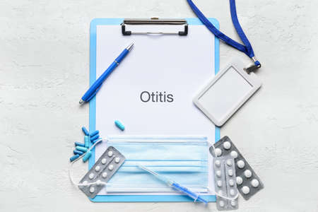 Clipboard with word OTITIS, badge and pills on white background
