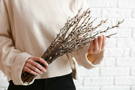Woman holding willow branches near brick wall