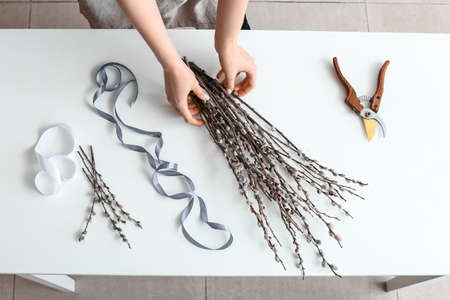 Woman making bouquet of willow branches on tableの写真素材