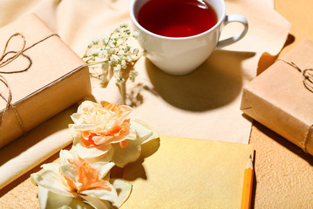 Cup of tea, beautiful daffodils and blank card on color backgroundの写真素材