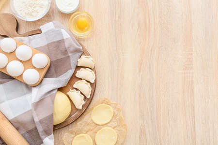 Composition with raw dumplings on wooden background
