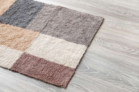 Colorful carpet on wooden floor, closeup