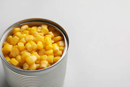 Opened tin can of corn kernels on white background