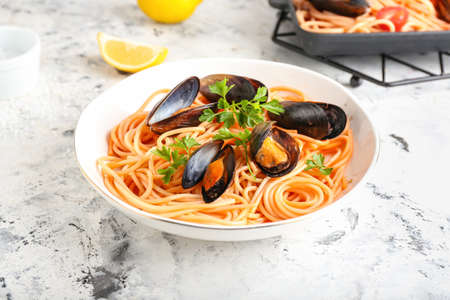 Plate of tasty Mussels Marinara with spaghetti on light backgroundの写真素材