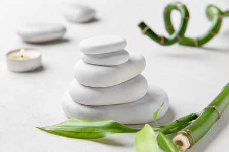 Stack of spa stones with bamboo branch on white backgroundの写真素材